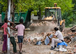 via  PTI : Children watch as bulldozer clears rubble during a demolition drive in Delhi. 
Credits